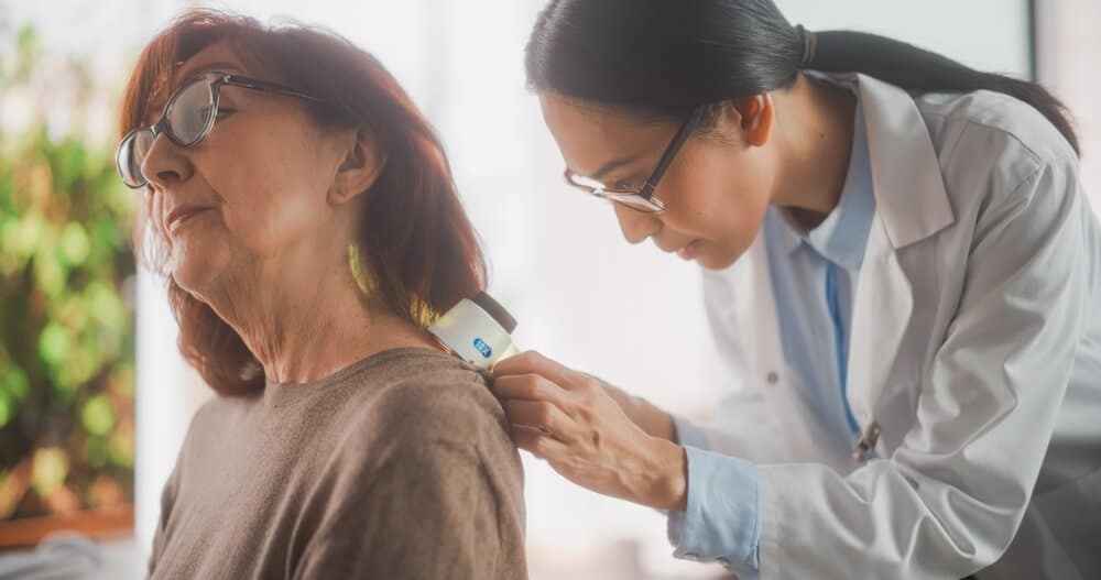 A female doctor performing a skin exam on a female patient.