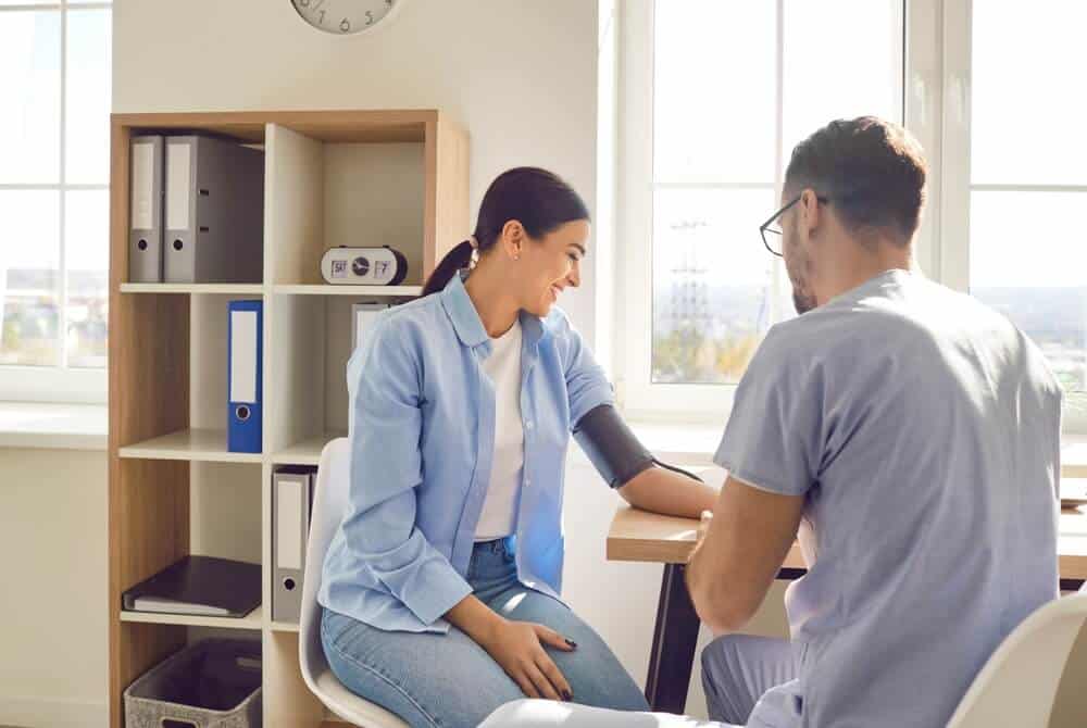 A male doctor using a blood pressure cuff on a patient.