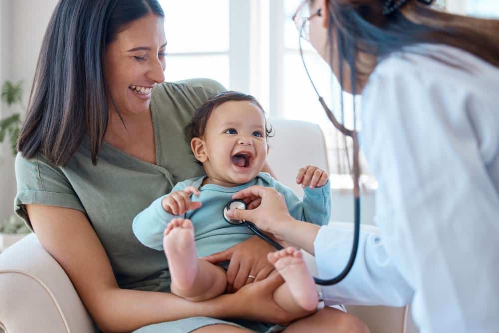 A mother holding her baby as the doctor does a checkup