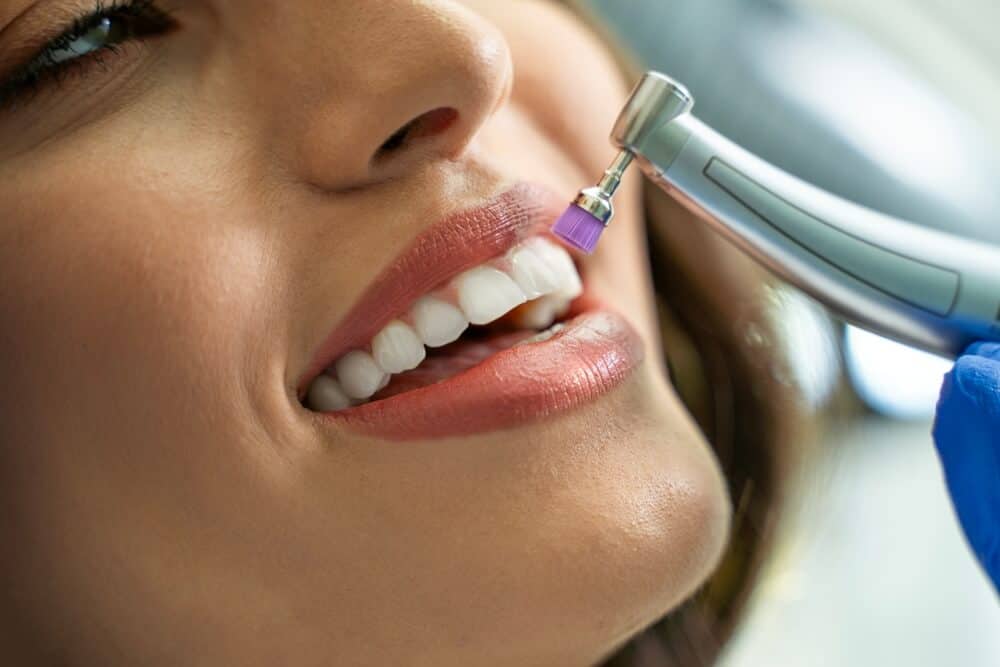A smiling female patient getting her teeth cleaned