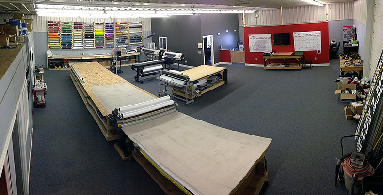 Wide-format print shop with staff working on large printers.